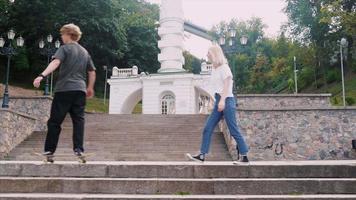 adolescenziale ragazzo e ragazza sospeso su a il parco con un' skateboard video