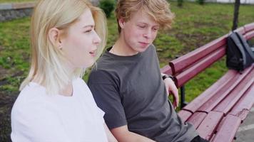 adolescenziale ragazzo e ragazza sospeso su a il parco con un' skateboard video