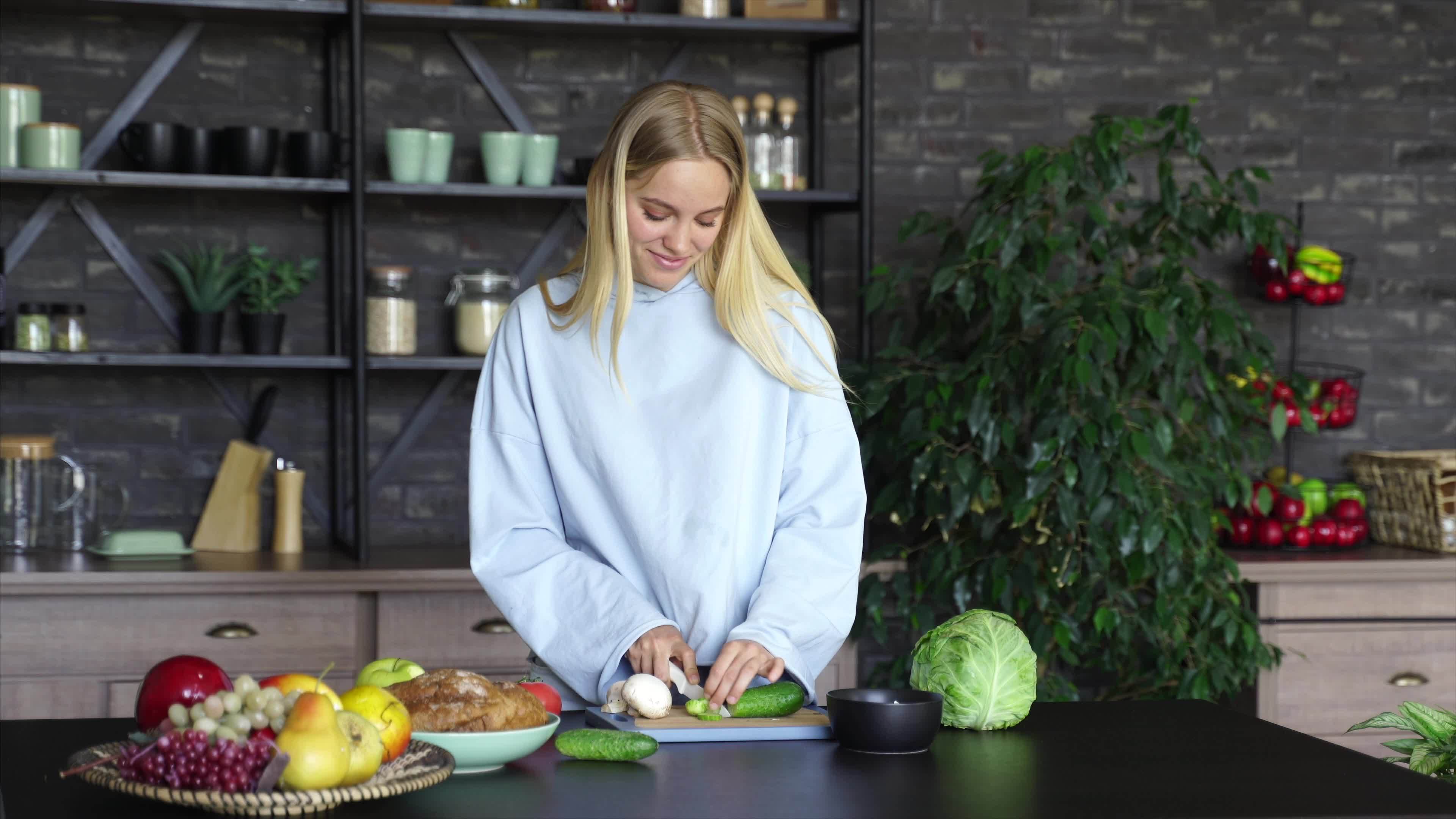 Young woman in a kitchen with fresh ingredients and smart phone device ...