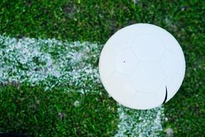 Soccer ball on grass at goal and stadium in background photo