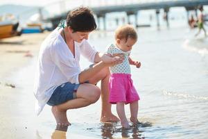 mamá y bebé en la playa se divierten foto