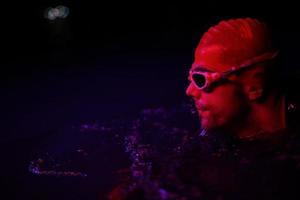 authentic triathlete swimmer having a break during hard training on night neon gel light photo