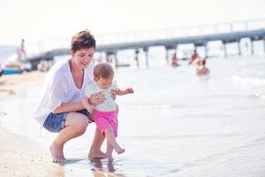 mamá y bebé en la playa se divierten foto