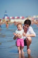 mamá y bebé en la playa se divierten foto