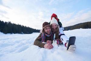 pareja romántica divertirse en la nieve fresca y tomar selfie foto