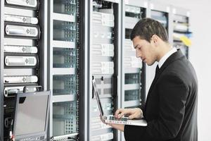 businessman with laptop in network server room photo