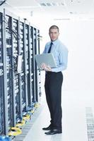 businessman with laptop in network server room photo