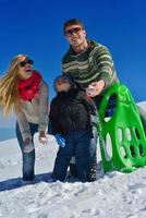 familia divirtiéndose en la nieve fresca en las vacaciones de invierno foto