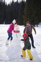 familia feliz construyendo muñeco de nieve foto