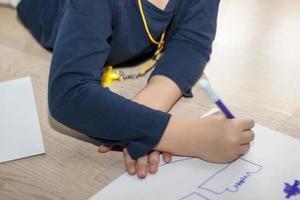 Unrecognizable kid sketching on a piece of paper. photo