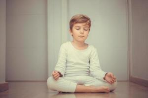 niño meditando y practicando yoga por la mañana. foto