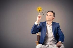 Businessman thinking of creative ideas and solutions while pointing at light bulb above his head. Copy space. photo