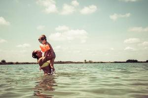 Cheerful mother and son having fun in water at the beach. photo