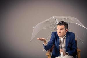 Businessman hiding under an umbrella and checking if it rains. Copy space. photo