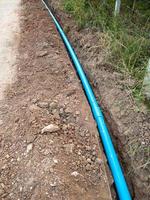 The new PVC pipe is laying in the trench along the concrete road. photo