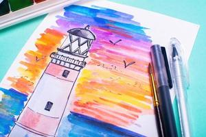 Lighthouse on coast of sea. Hand drawn beacon. Sketch with paints and pens on the table. photo