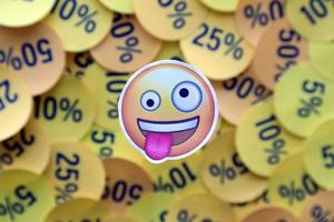 Ternopil, Ukraine - May 8, 2022 Crazy emoji sticker on large amount of yellow stickers with percentage values for black friday or cyber monday photo