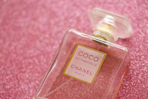 TERNOPIL, UKRAINE - SEPTEMBER 2, 2022 Coco Mademoiselle Chanel Paris worldwide famous french perfume bottle on shiny glitter background in purple colors photo