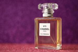 TERNOPIL, UKRAINE - SEPTEMBER 2, 2022 Chanel Number 5 Eau Premiere worldwide famous french perfume bottle on shiny glitter background in purple colors photo