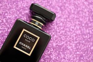 TERNOPIL, UKRAINE - SEPTEMBER 2, 2022 Coco Noir Chanel Paris worldwide famous french perfume black bottle on shiny glitter background in purple colors
