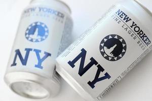 TERNOPIL, UKRAINE - JULY 18, 2022 Two cans of New Yorker fine lager beer with original logo and design on white paper background photo
