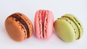 three macaroons in green, red and brown against white background photo