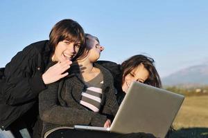 grupo de adolescentes trabajando en una laptop al aire libre foto