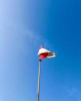 The red and white flag flutters in the sky against the blue sky background photo