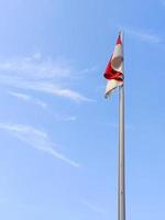 The red and white flag flutters in the sky against the blue sky background photo