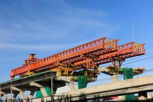 autopista de la ciudad en construcción con un enorme equipo mecánico moderno. gran grúa de máquina pesada sobre pilares gigantes durante la construcción de vías rápidas. foto