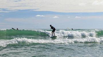 Young boy wearing swimming goggles stable stands on soft board while practicing surfing in beginner's class. photo