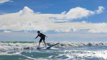 Young boy wearing swimming goggles stable stands on soft board while practicing surfing in beginner's class. photo