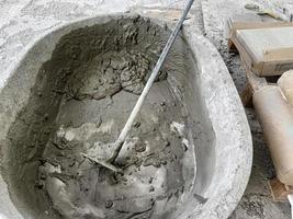 Make concrete with sand, water, cement in tray. Mix ingredients with hoes for walkway tile flooring construction photo