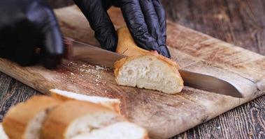 corte una baguette de trigo en una tabla de cortar mientras cocina foto