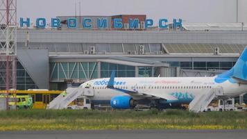 nowosibirsk, russische föderation 15. juli 2022 - boeing 737 pobeda airlines am terminal des flughafens tolmachevo. Flughafenmitarbeiter steigen die Treppe zum Flugzeug hinauf video