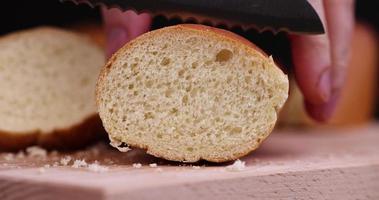 Cutting a wheat baguette on a cutting board photo