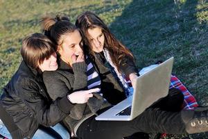 group of teens working on laptop outdoor photo