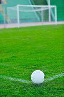 Soccer ball on grass at goal and stadium in background photo