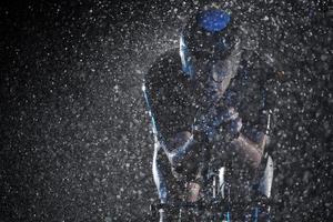 triathlon athlete riding bike  fast on rainy night photo