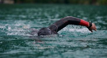 triathlon athlete swimming on lake wearing wetsuit photo