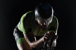 atleta de triatlón montando bicicleta rápido por la noche foto