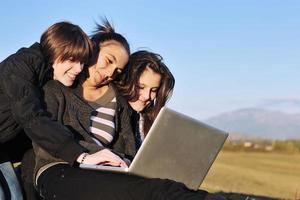 grupo de adolescentes trabajando en una laptop al aire libre foto