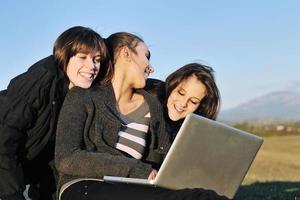 group of teens working on laptop outdoor photo