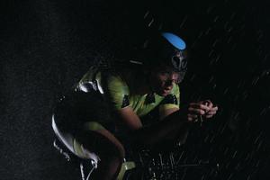 triathlon athlete riding bike  fast on rainy night photo