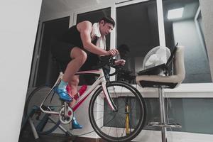 Man cycling on the machine trainer he is exercising in the home at night playing online bike racing game photo