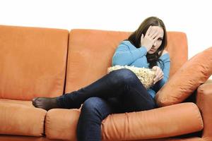 young woman eat popcorn on orange sofa photo