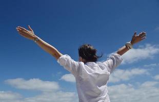 mujer joven feliz con los brazos extendidos al cielo foto