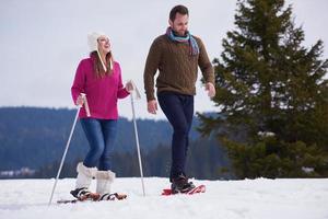 couple having fun and walking in snow shoes photo