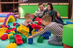 padres jóvenes y niños divirtiéndose en la sala de juegos para niños foto