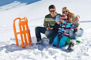 familia divirtiéndose en la nieve fresca en invierno foto